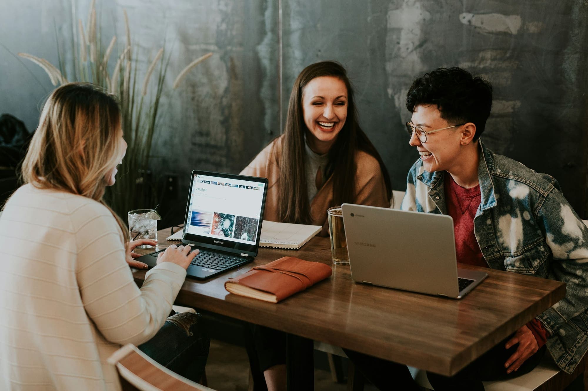 Three people laughing while working on laptops together