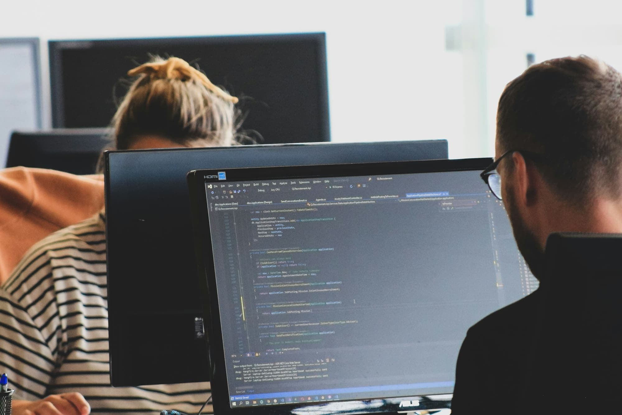 Two developers working on code at monitors